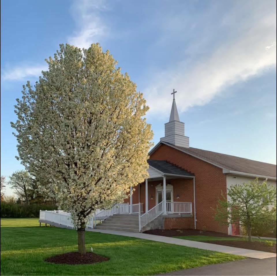 Reynoldsburg Free Will Baptist Church, with its brick exterior, white steeple, and flowering tree